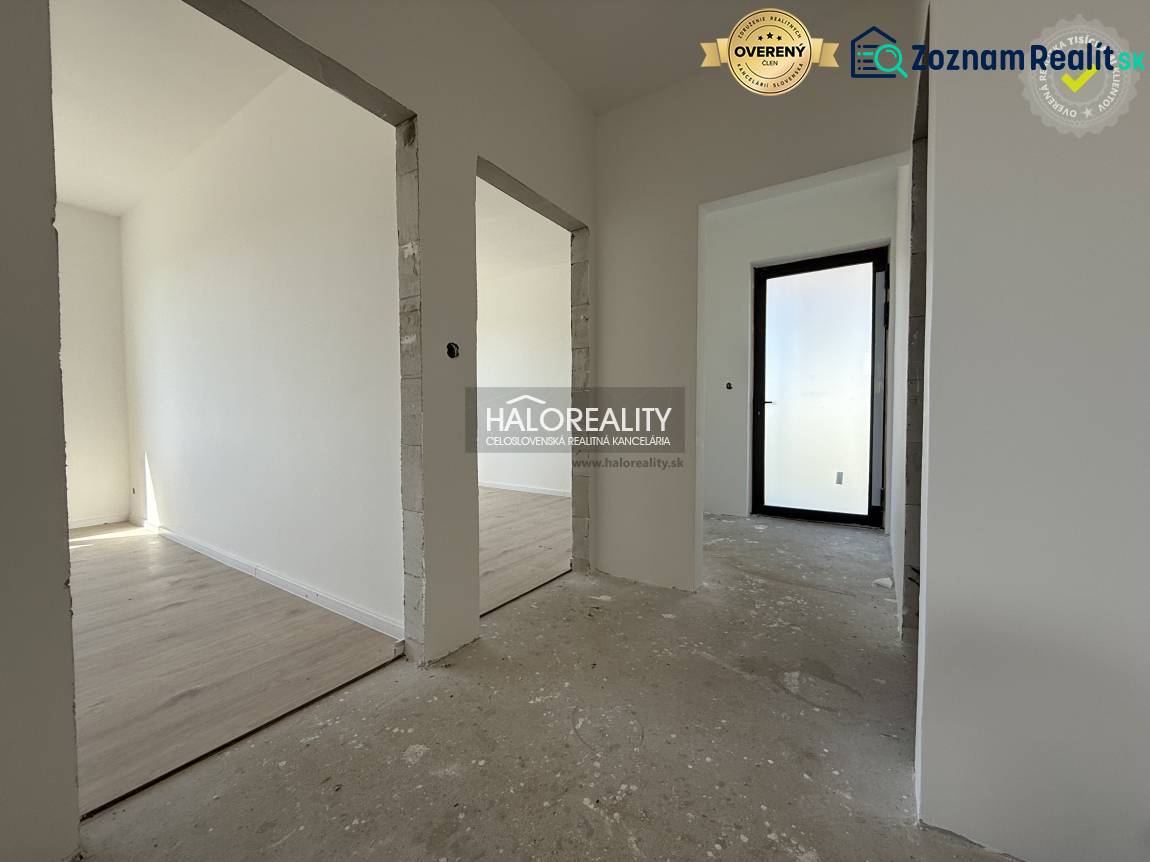 The interior of a family house with a concrete floor and white walls, through open doors.