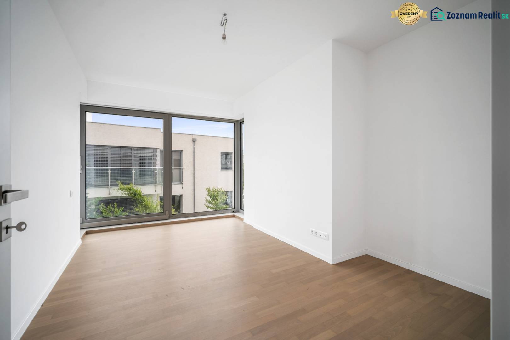 A bright room with a large window and a wooden decor floor in a 4-room apartment.