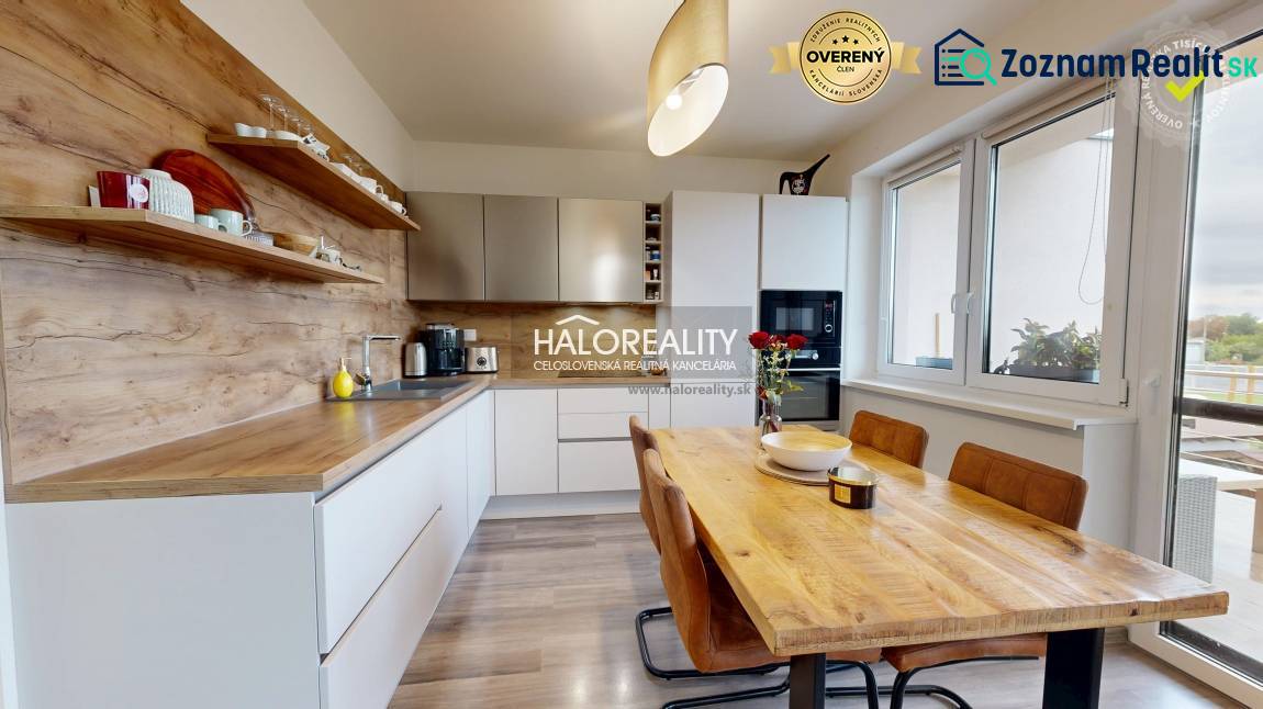 The kitchen of a three-room apartment with a wooden decor floor and a dining table.