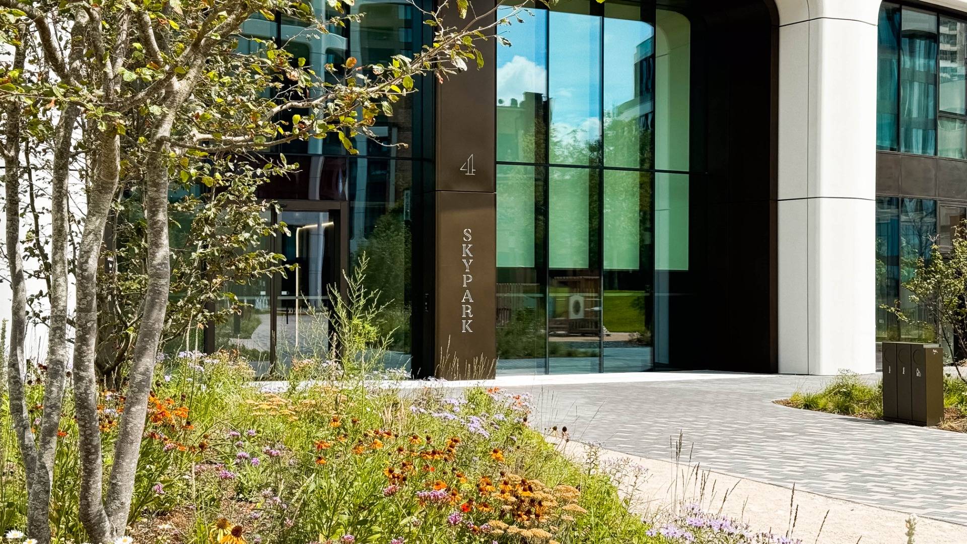 Entrance to the Sky Park building in Bratislava on Bottova, surrounded by trees and flowers.