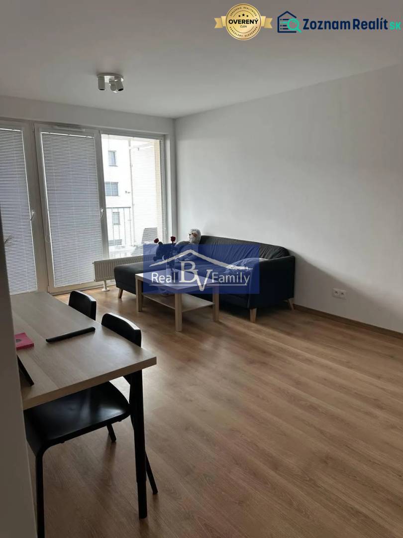 Living room in a two-room apartment with a wooden decor floor and a dining table.