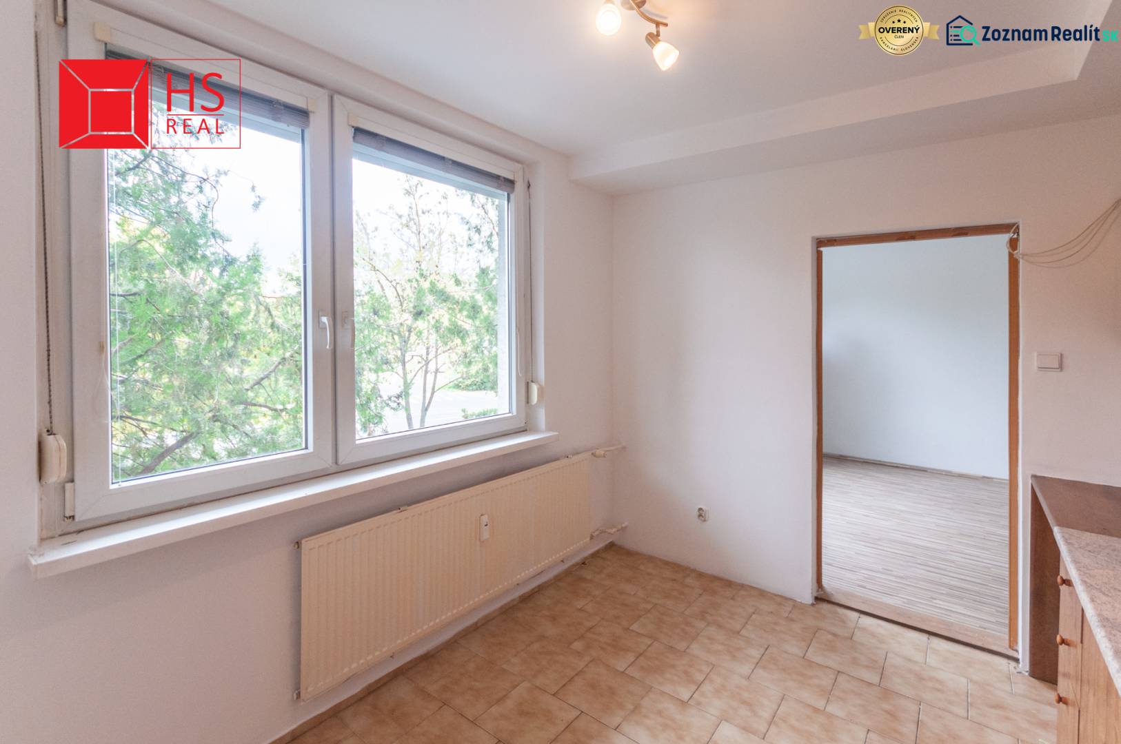 A room with a large window, tiles, and a wooden decor floor in a 3-room apartment.