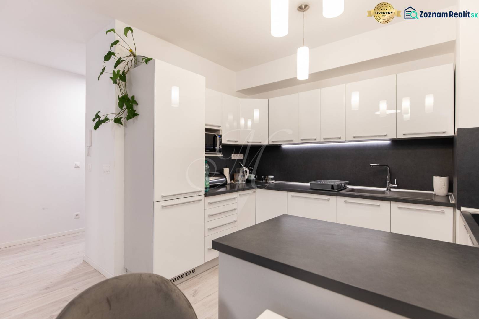 A kitchen unit with white cabinets and a black countertop in a two-room apartment.