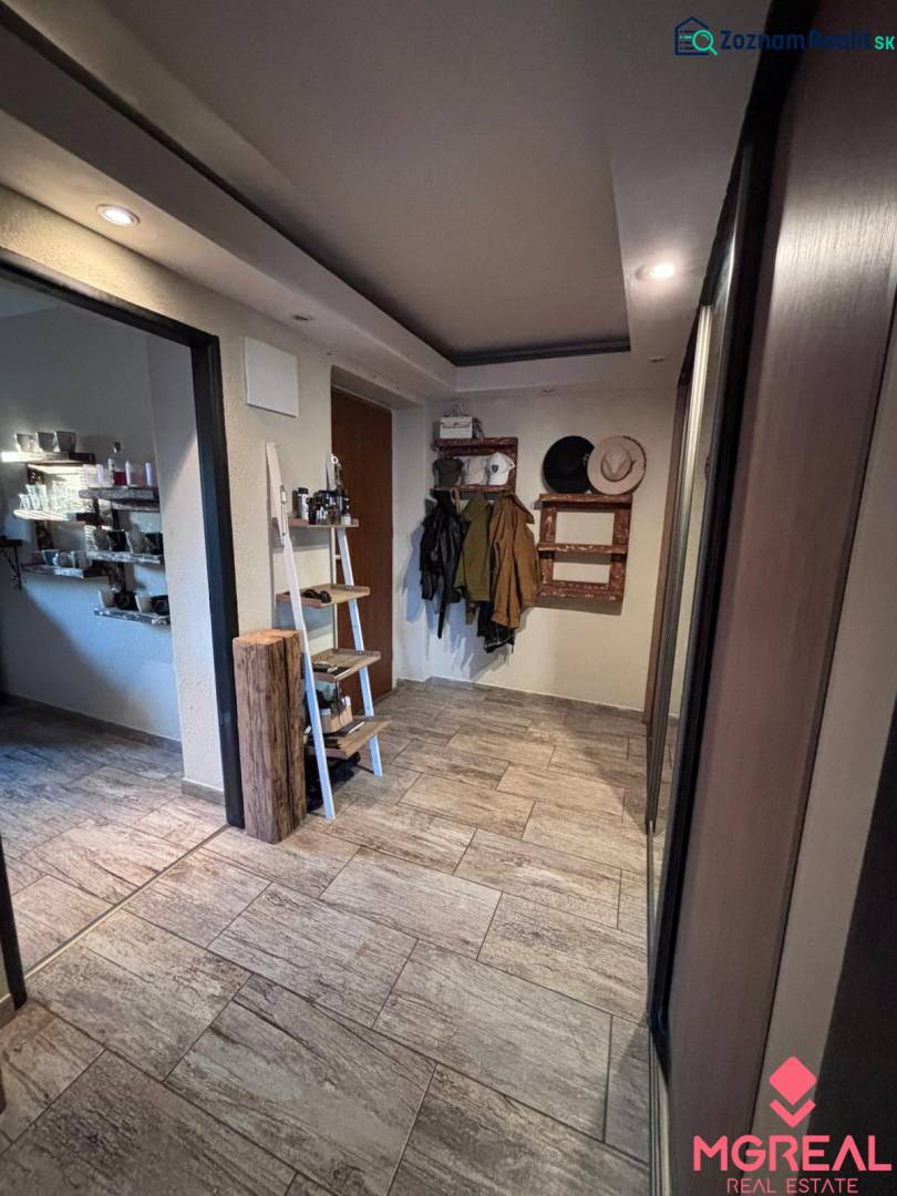 A hallway in a 2-room apartment with a coat rack, shelves, and tiles with a wooden design.