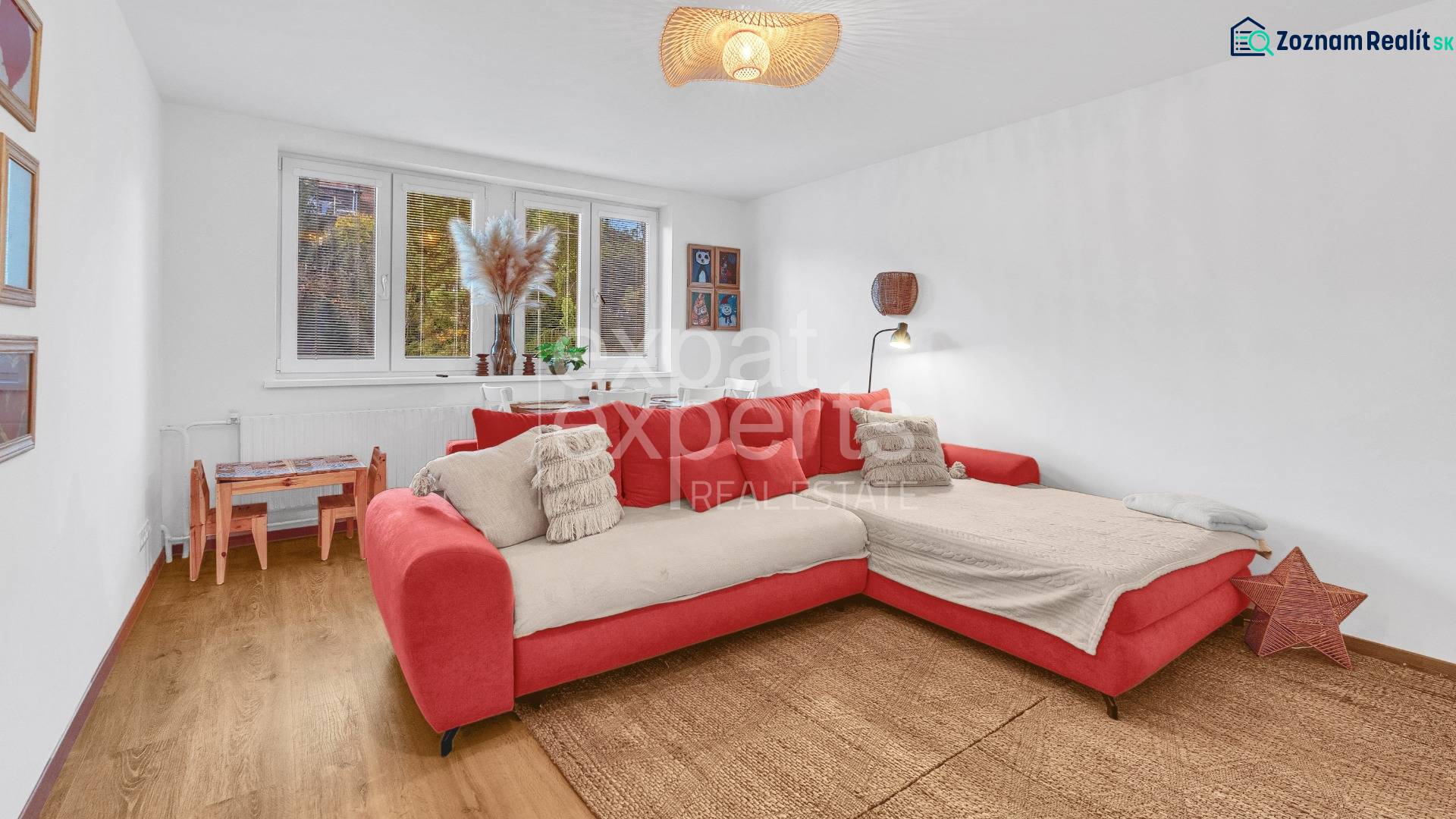 A living room with a red sofa and a wooden-patterned floor in a family house.