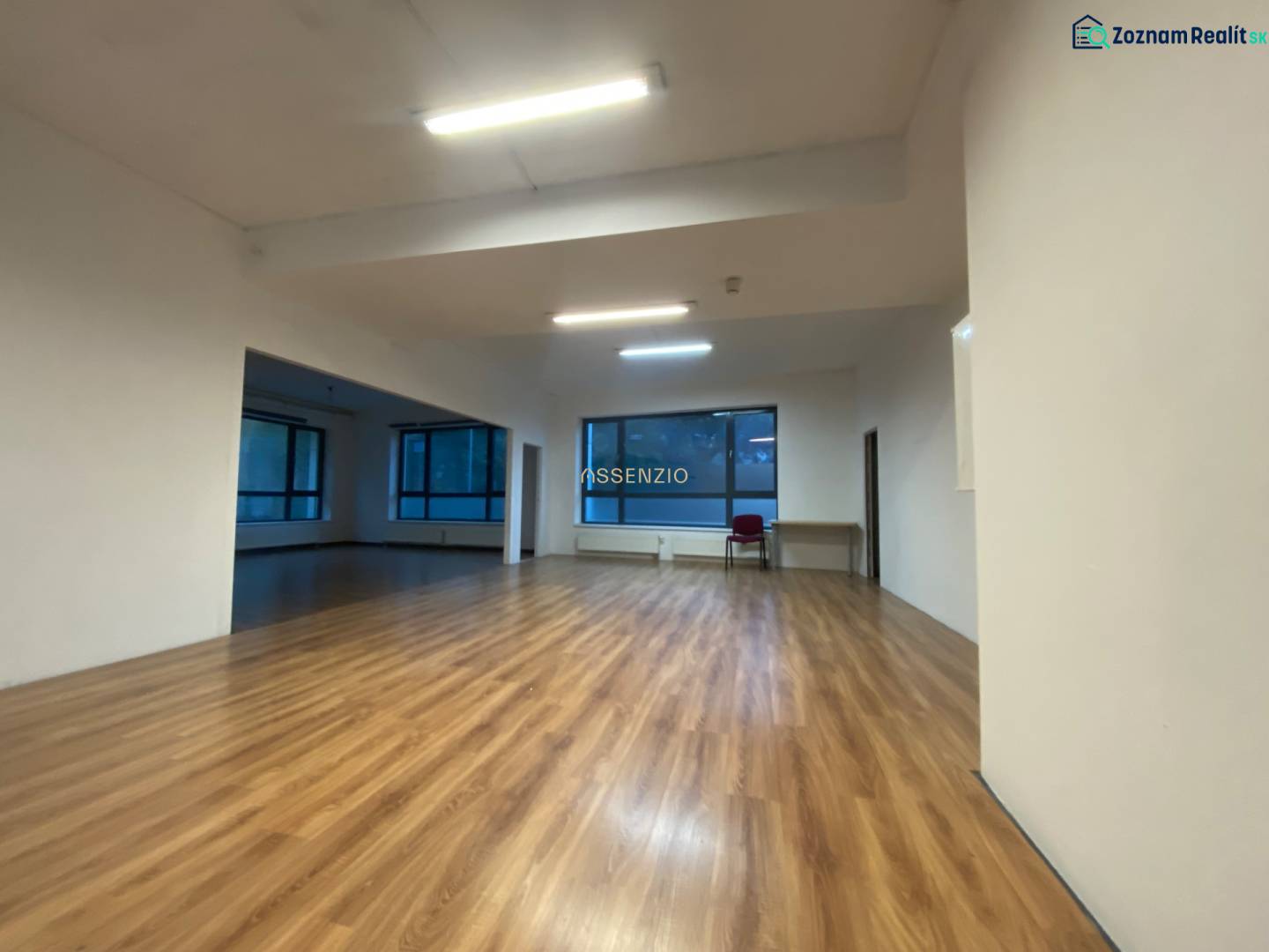 Commercial spaces with wood-patterned flooring and large windows.