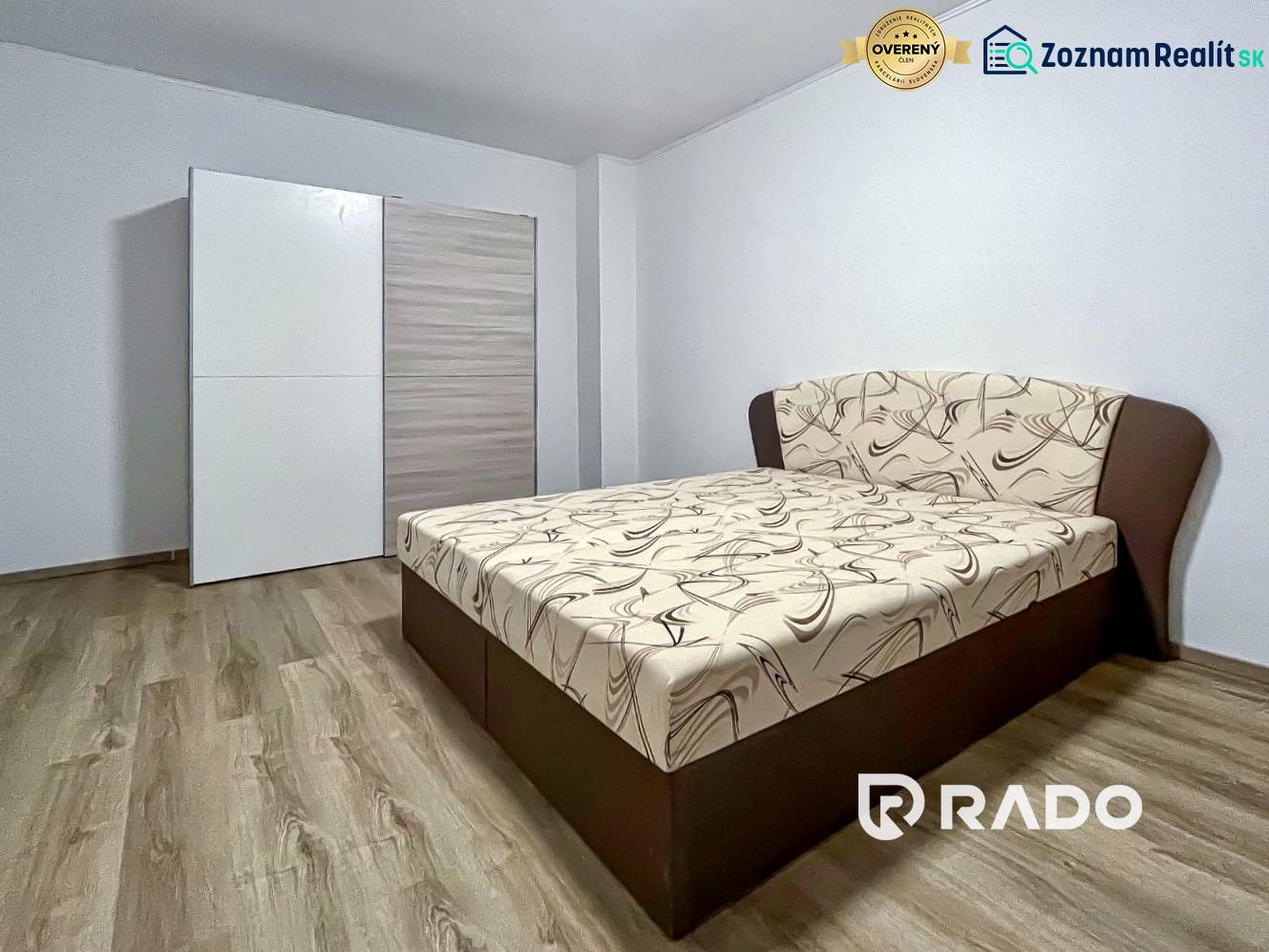 Bedroom in a 2-room apartment with a bed and a wardrobe, floor with wood decor.