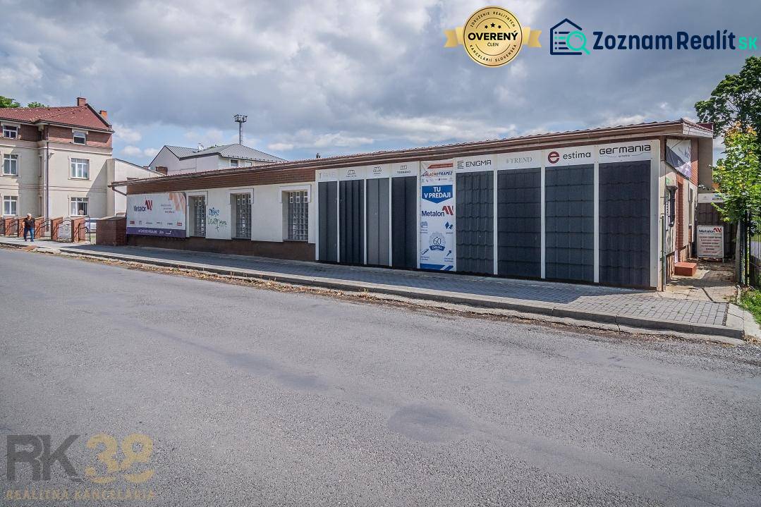The building on Halatova Street in Poprad with a parking lot and trees in the background.