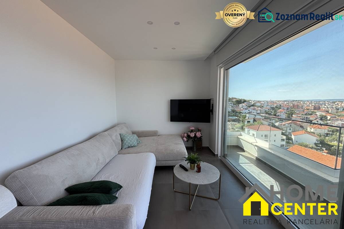 Living room in a villa with a sofa, television, and a view of the city of Trogir.