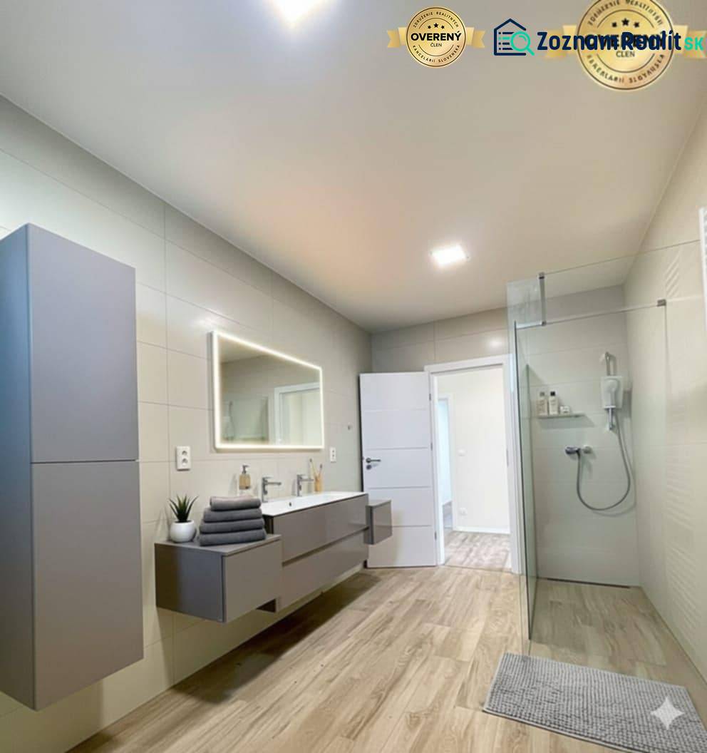 Bathroom with wood-patterned flooring, shower enclosure, and furniture in a family house.