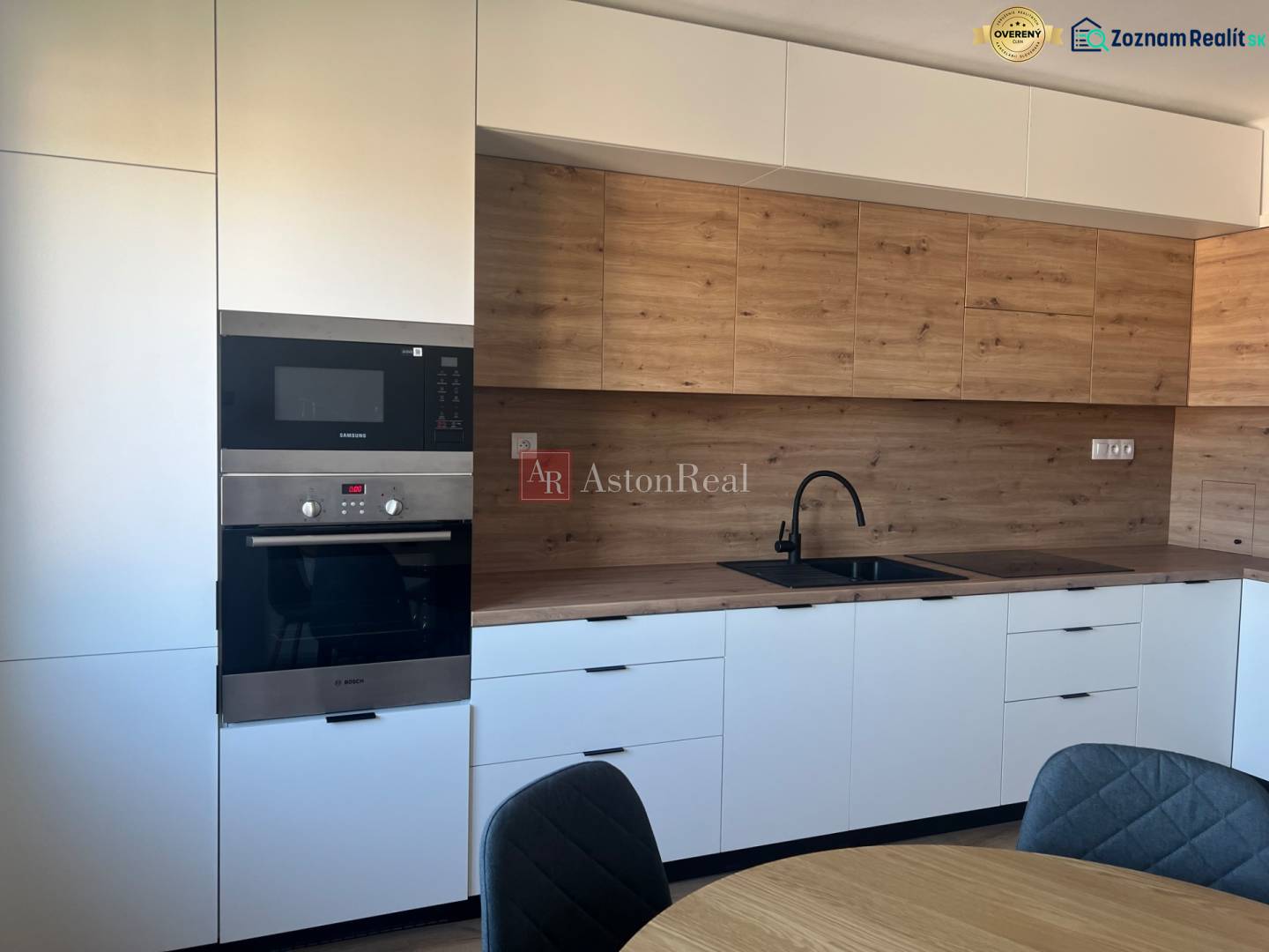 A kitchen with white cabinets and a wood-patterned floor in a studio apartment.