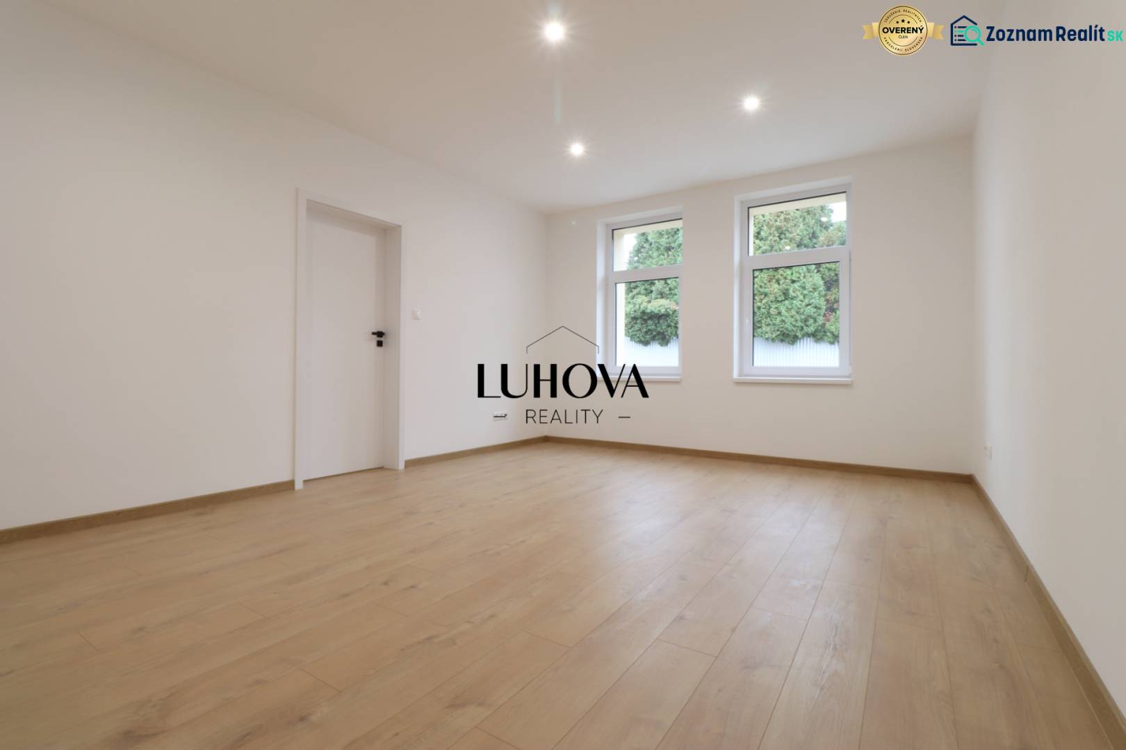 A spacious room with a wooden decor floor and white walls in a family house.