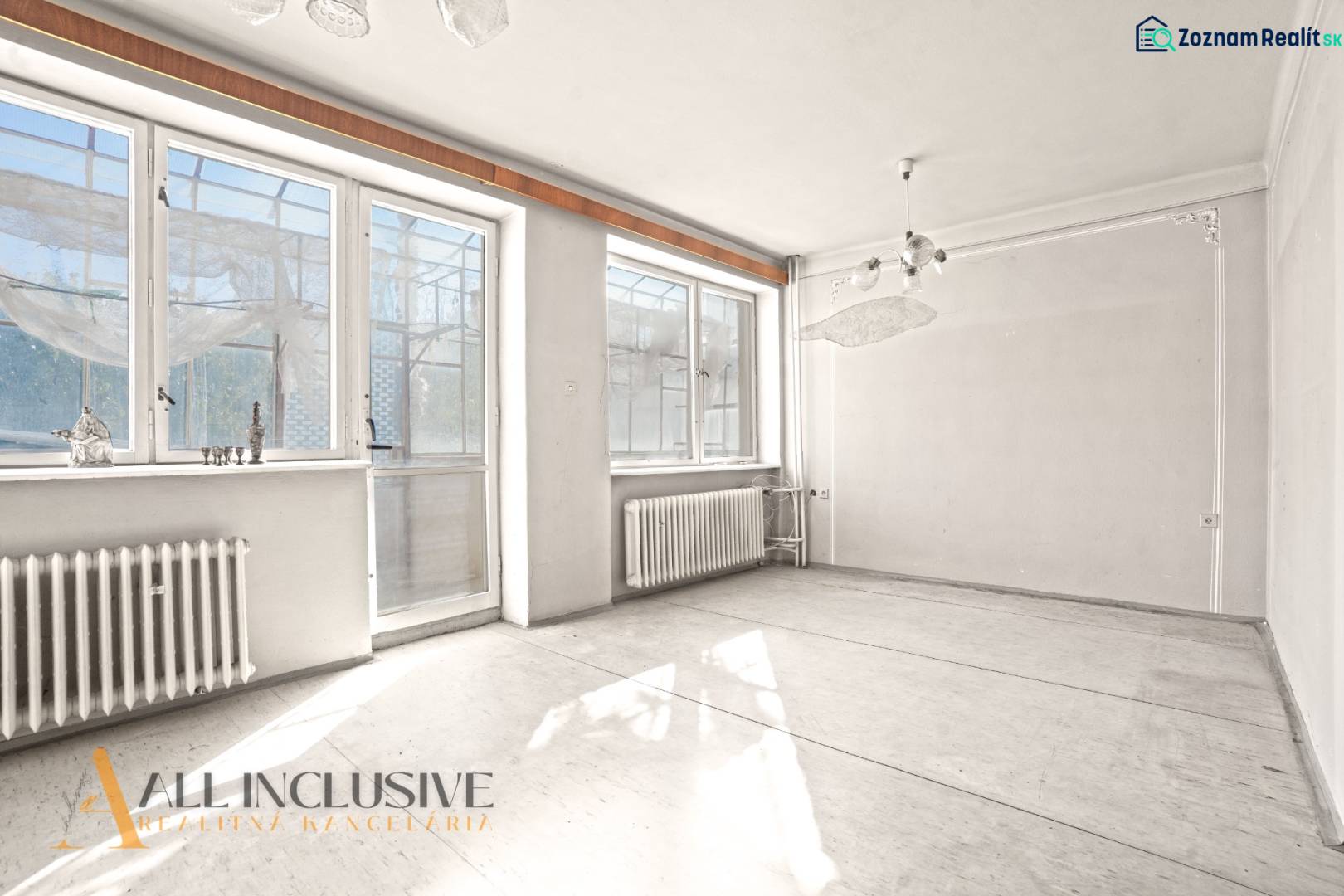 An empty room with large windows and radiators in a family house.