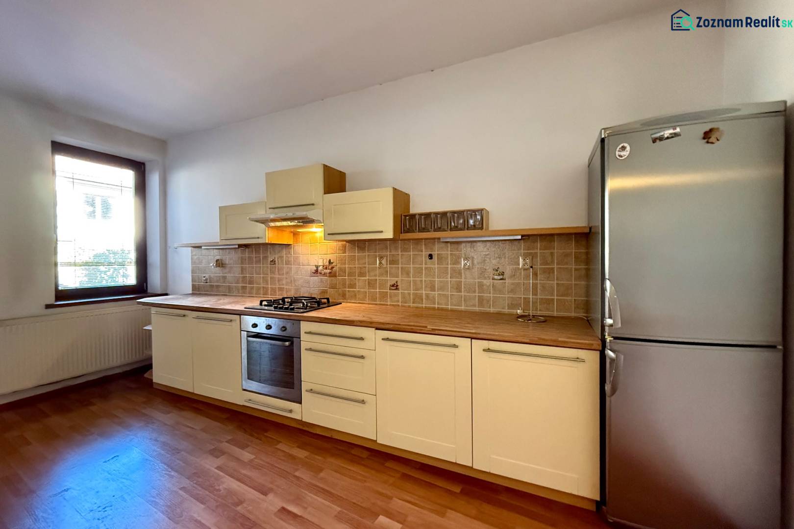 A kitchen in a family house with a wooden decor floor and a stainless steel refrigerator.