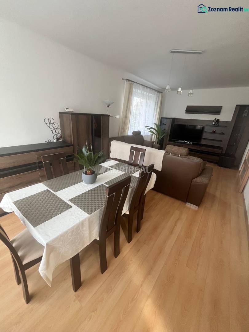 Dining room in a 3-room apartment with a sofa, wood-patterned flooring, and a television.