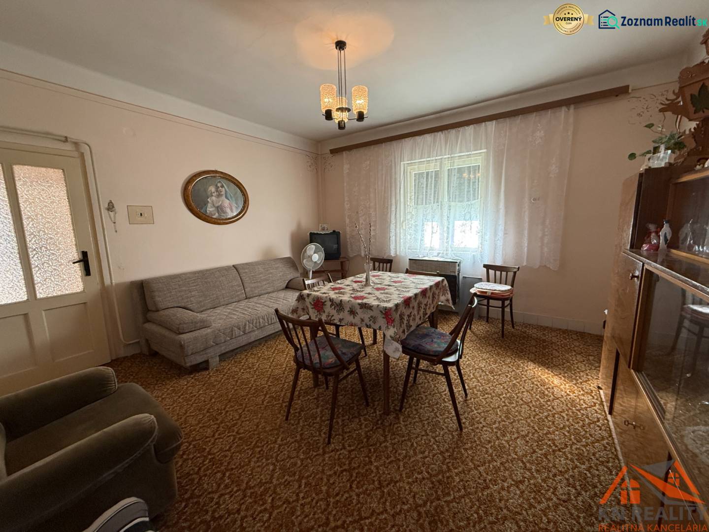 Living room in a family house with a carpet, sofa, and dining table with chairs.