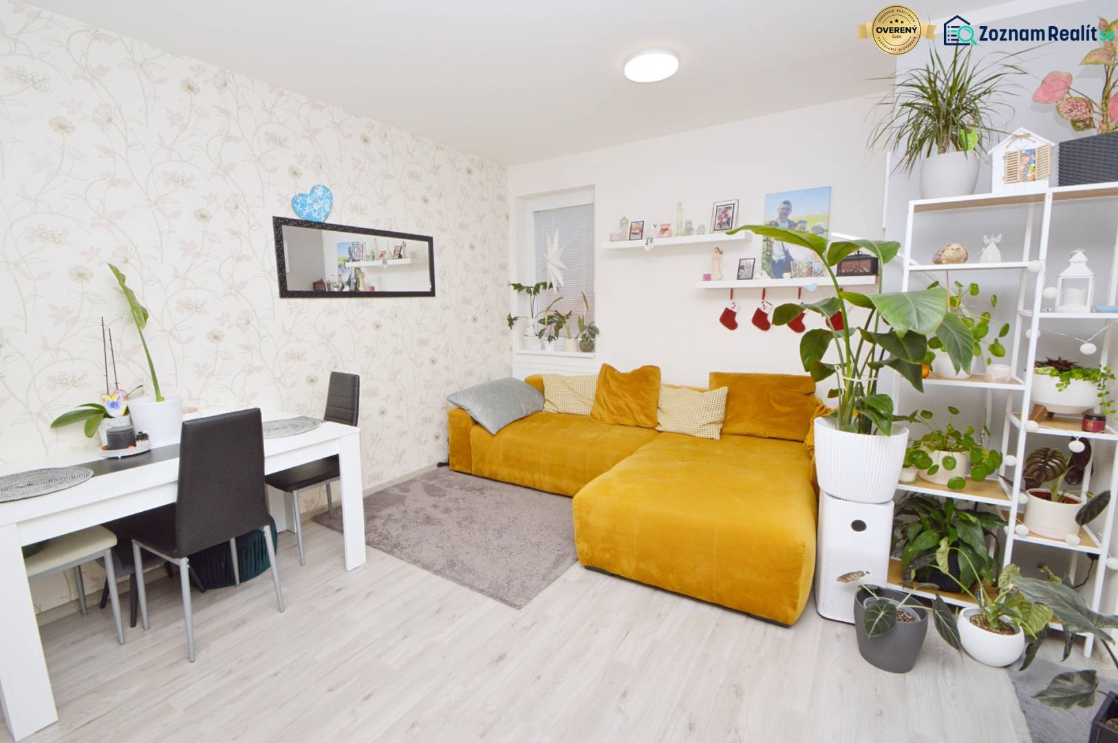 Living room in a 3-room apartment with a yellow sofa, table, and plants, floor with wood decor.