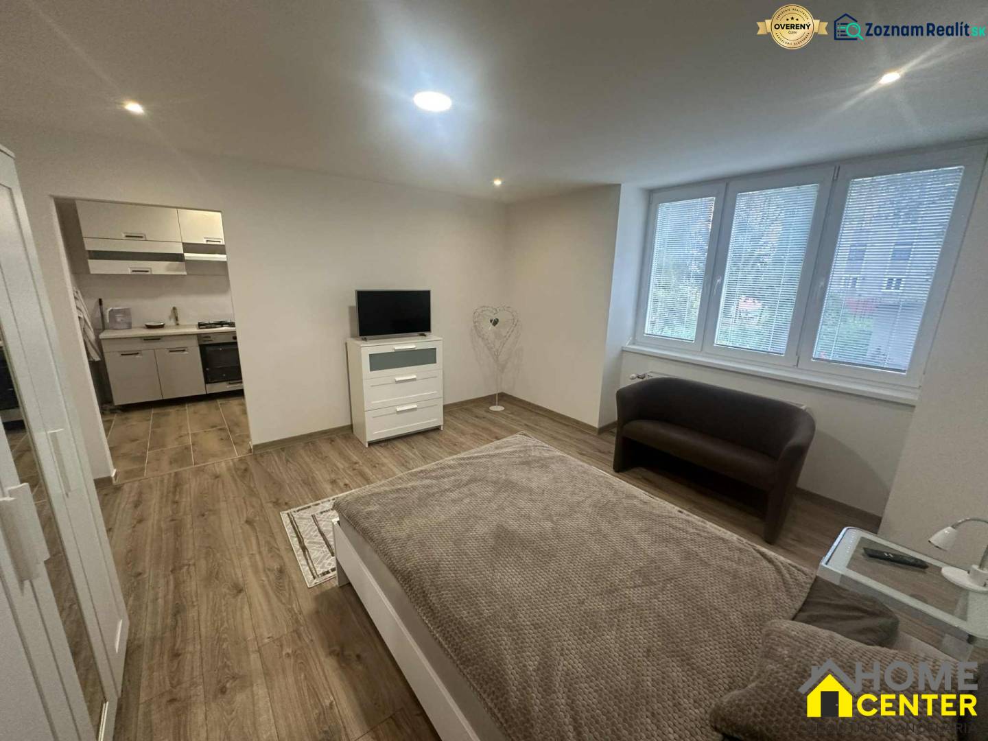 Living room in a one-room apartment with a wooden decor floor and a view outside.