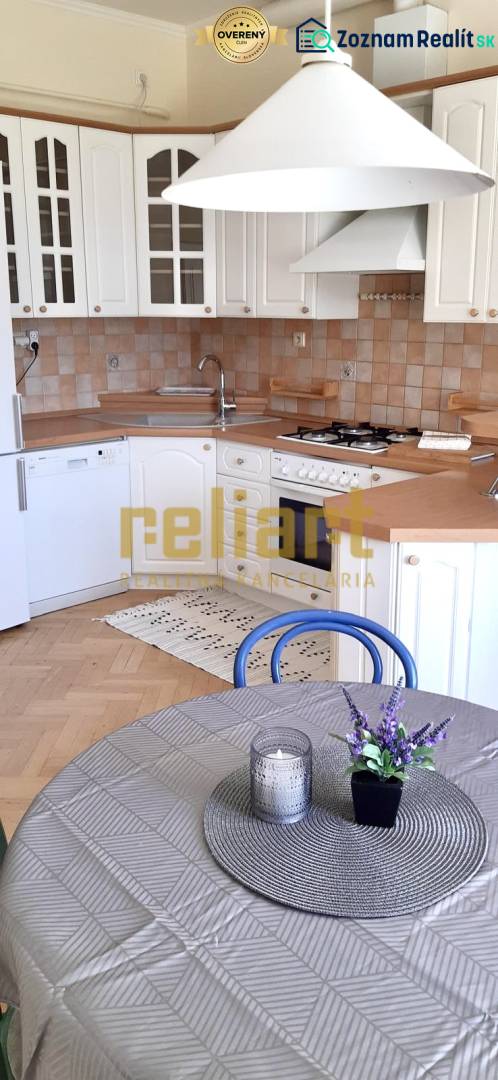 A kitchen with white cabinets, a wooden decor floor, and a table in a 4-room apartment.