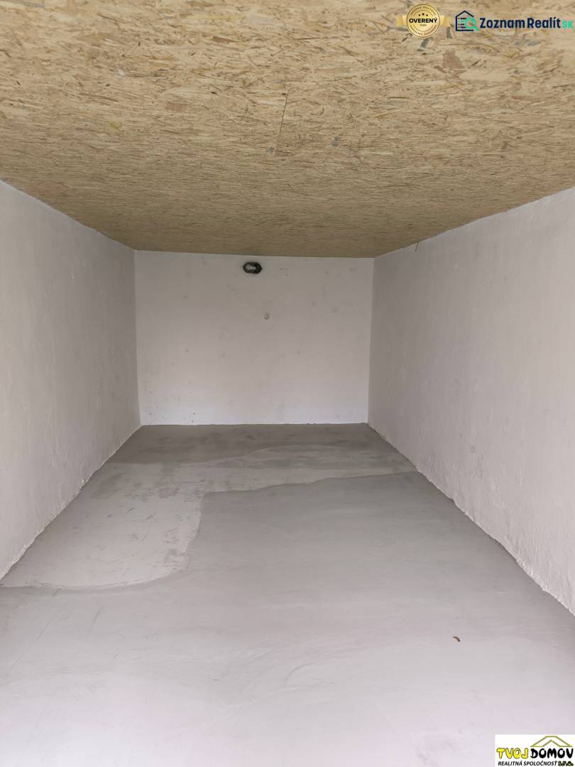 White garage with a wooden ceiling and concrete floor on M. R. Štefánika Street in Detva.