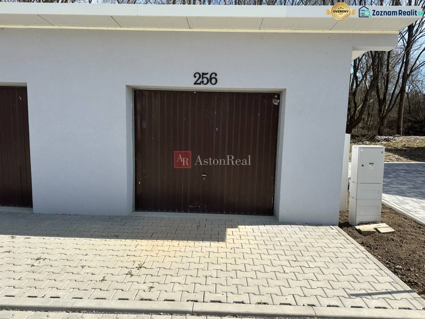 Garages in Liptovské Kľačany, simple design, white facade, brown gate, and paving.
