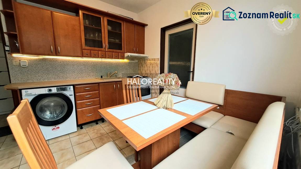 A kitchen in a studio apartment with a wooden decor and a corner sofa.