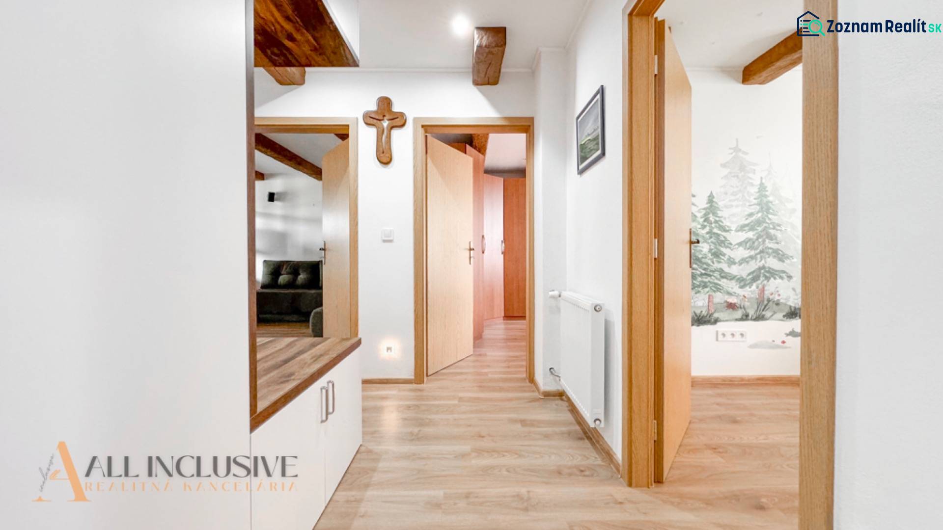 A hallway in a 3-room apartment with a wooden decor floor, wooden beams, and a drawing on the wall.