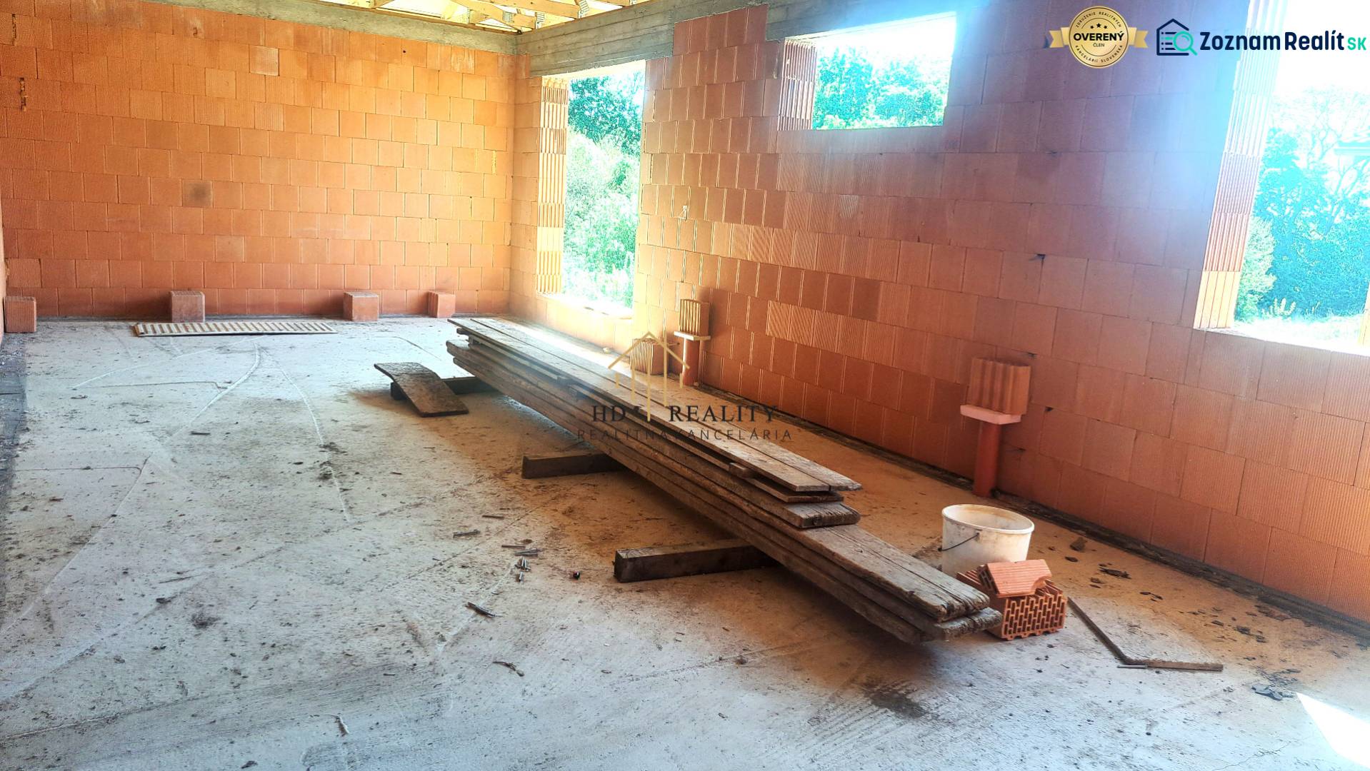 Construction of a family house in Hokovce with raw brick walls and wooden boards on the ground.
