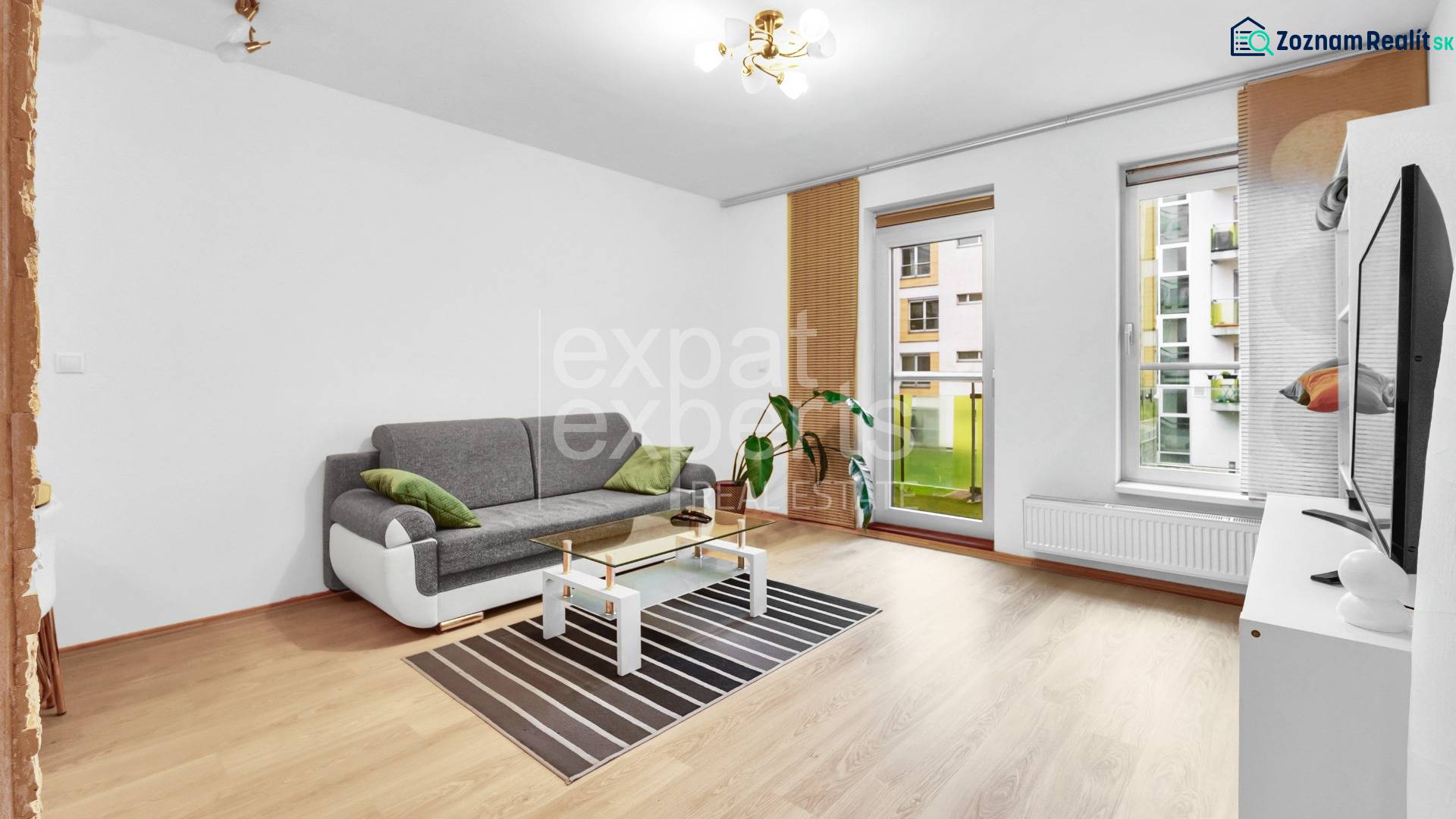 Living room in a two-room apartment with a sofa, table, and windows with a view.