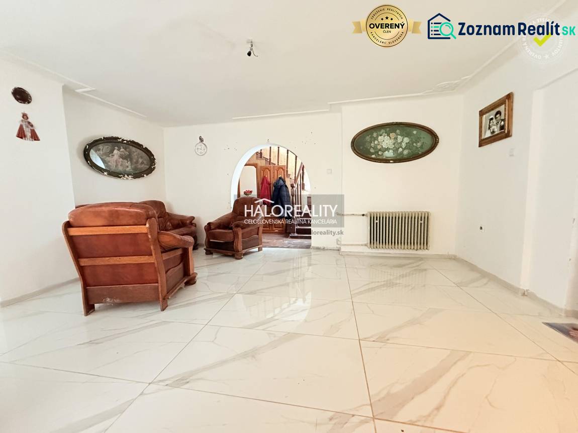 The interior of a family house with a white floor and brown furniture, decorative paintings on the walls.