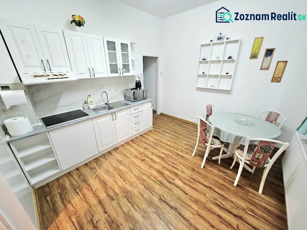 Kitchen in a family house with white cabinets and wood-patterned flooring.