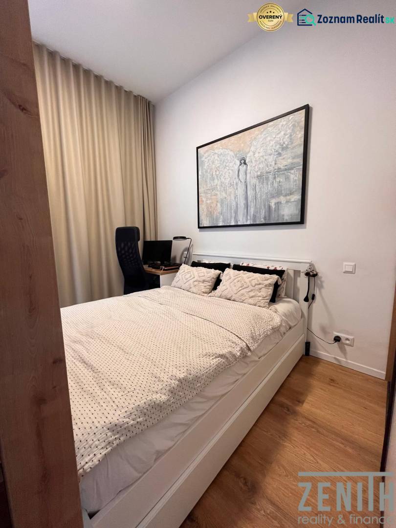 A bedroom with a bed, a desk, and a wooden decor floor in a studio apartment.