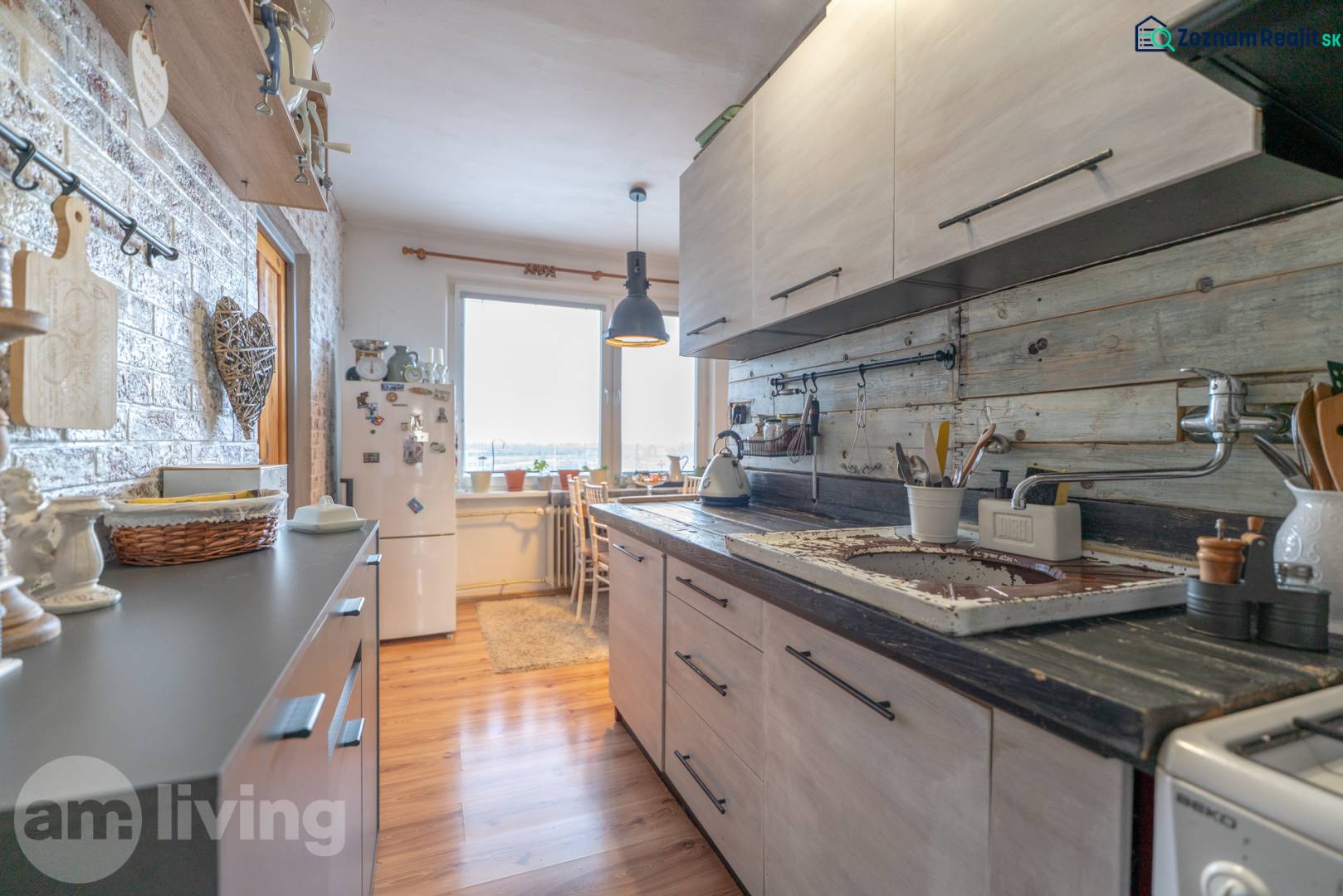 A kitchen in a 3-room apartment with a wooden decor floor and wall decorations.
