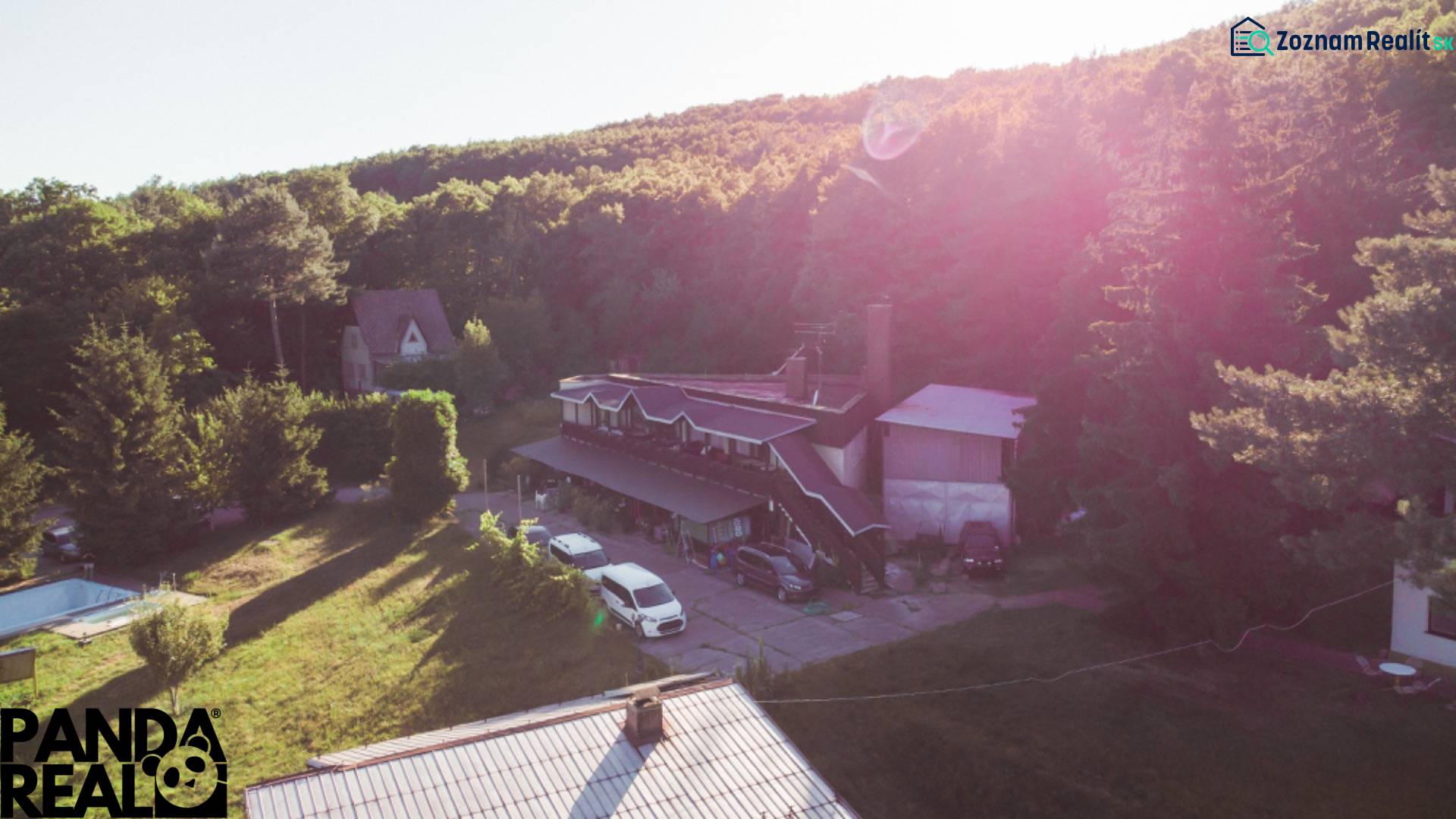 A cottage in Prašice surrounded by trees with a spacious yard and vehicles nearby.