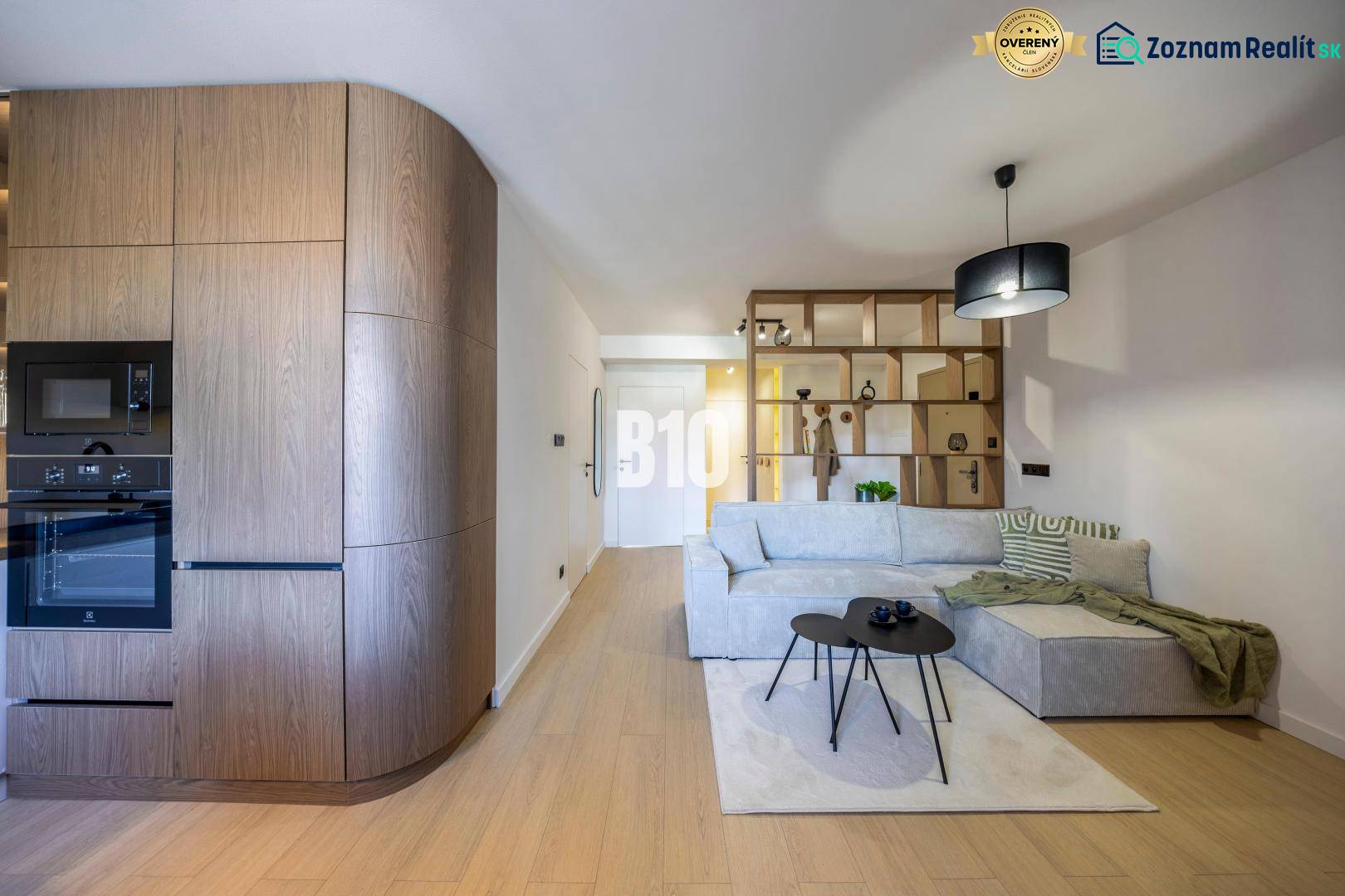 Living room in a 3-room apartment with a sofa, wooden decor, and a built-in kitchen.