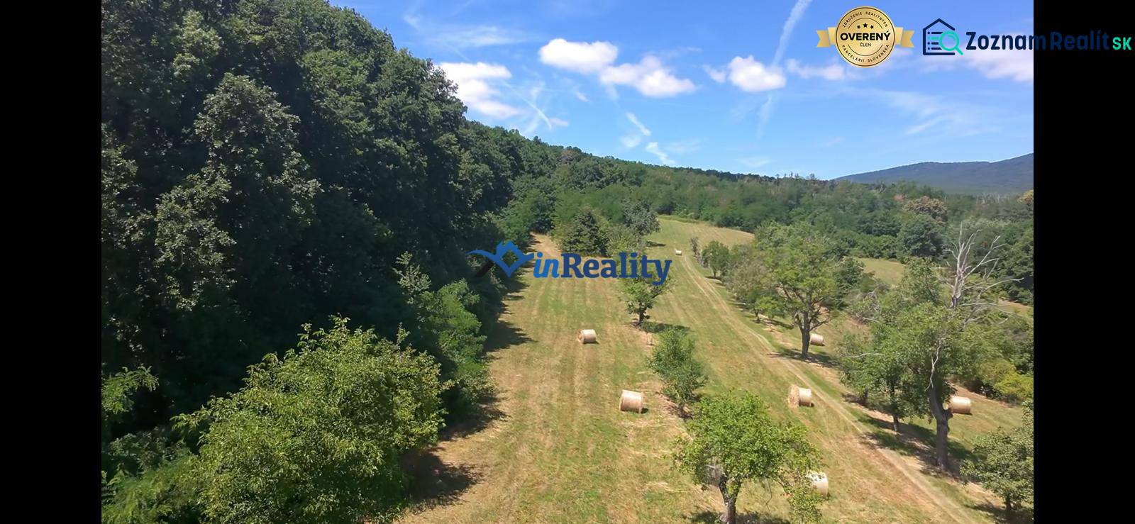 A meadow in Čaradice surrounded by forest, ideal for commercial plots with hay bales.