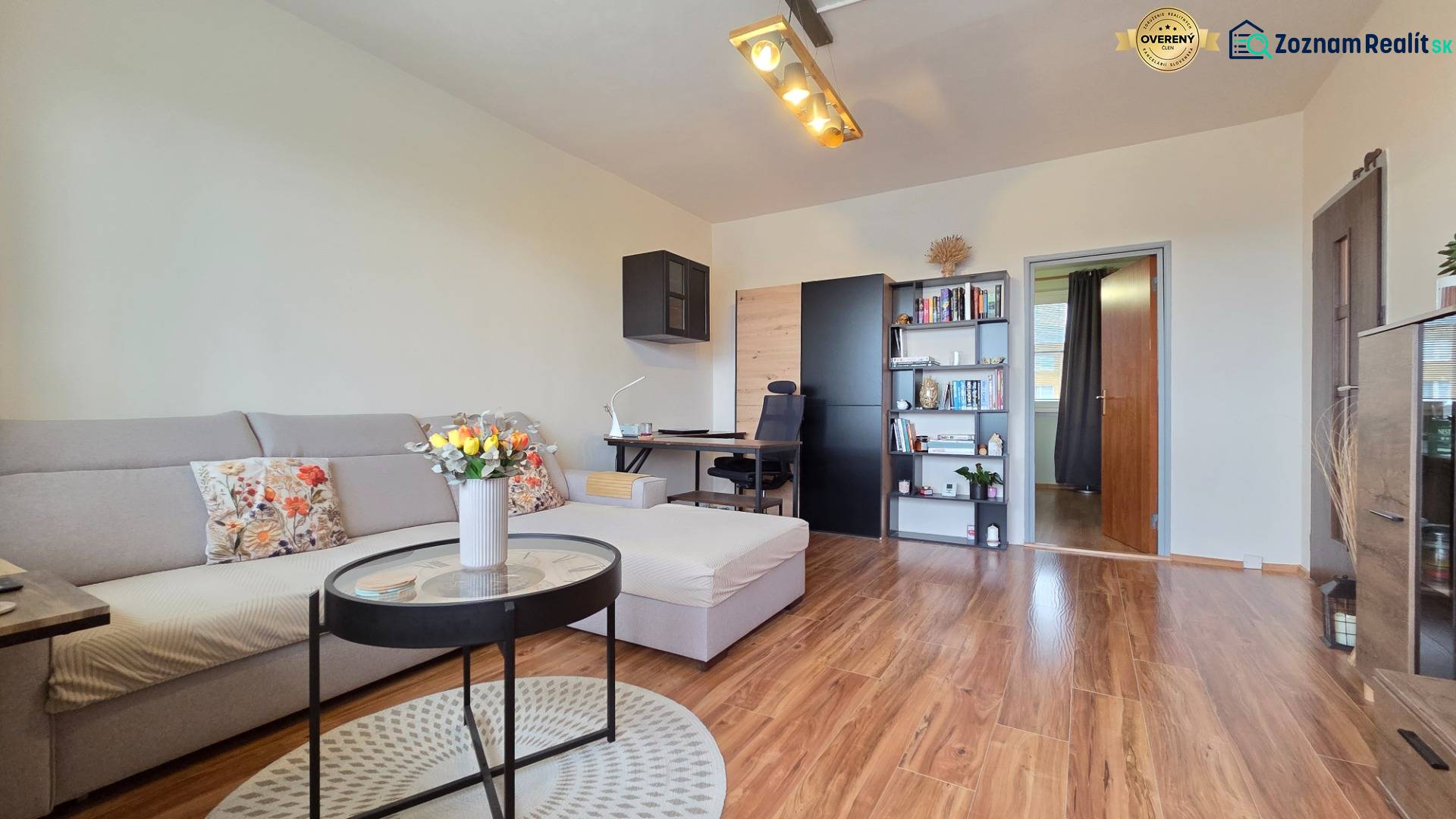 Living room in a three-room apartment with a wooden decor floor and a light sofa.
