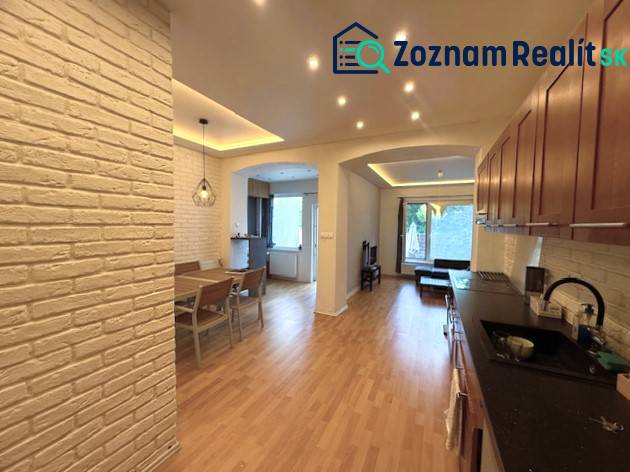 A family house with white brick walls, a wooden decor floor, and a dining table.