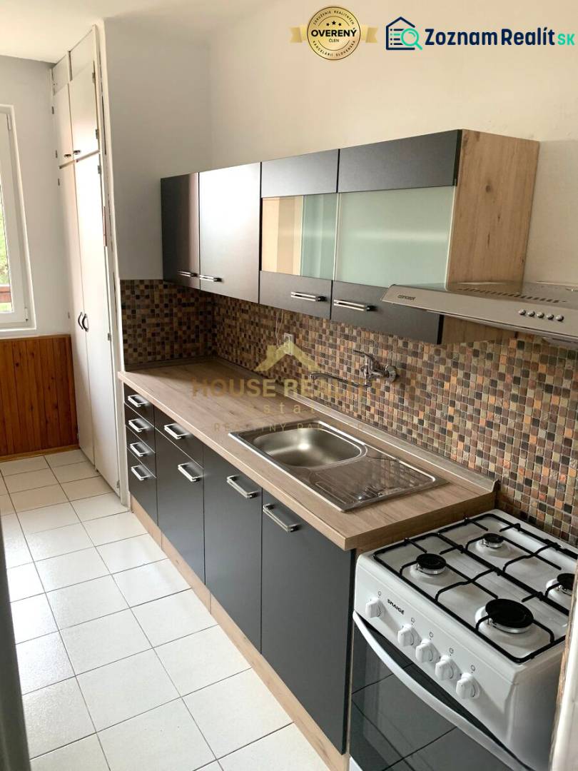 A kitchen with a dark cabinet, mosaic tiles, and a white floor in a 2-room apartment.