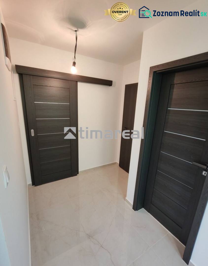 A hallway in a 3-room apartment with dark sliding doors and a light floor.