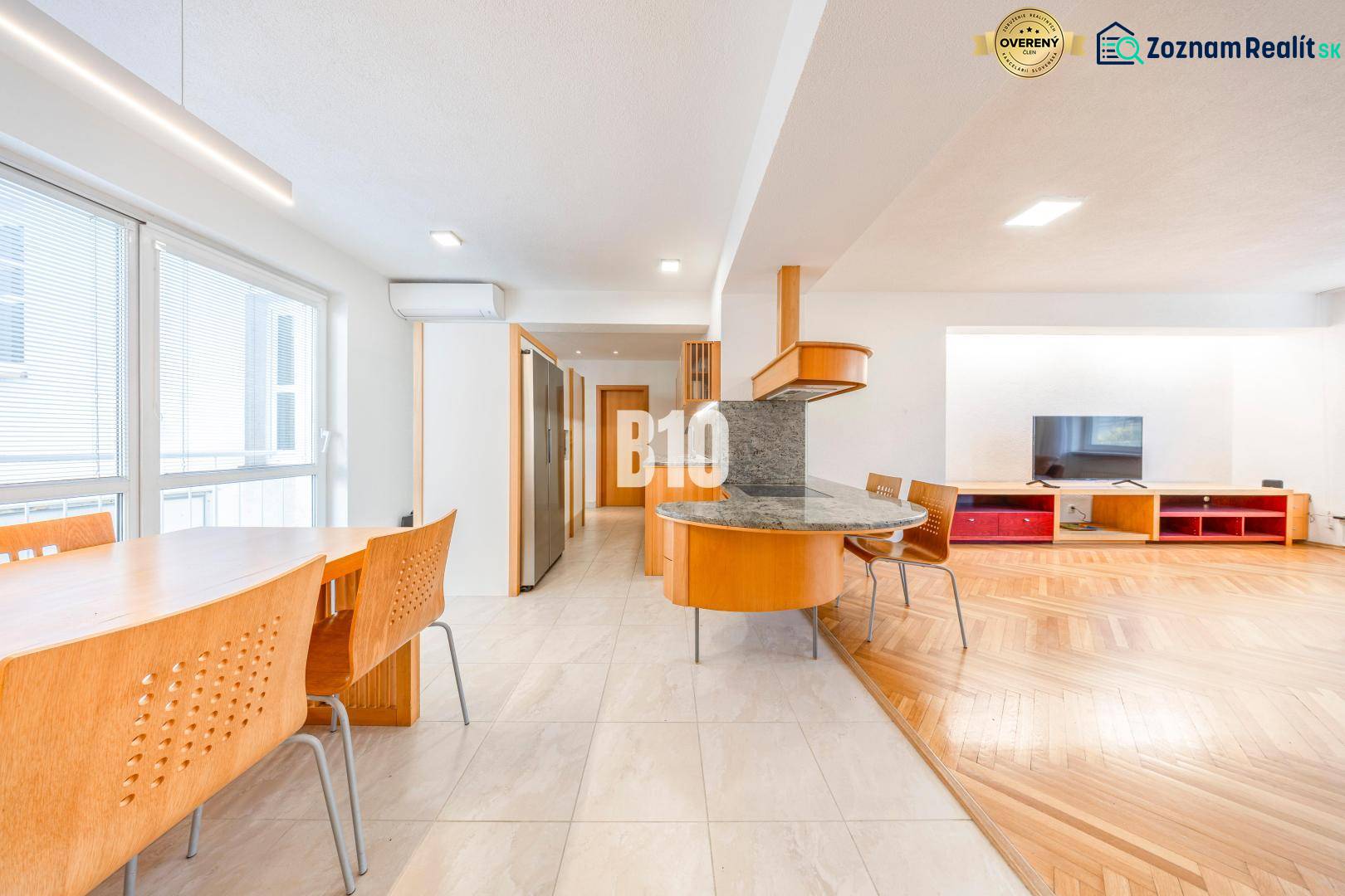A bright kitchen of a 3-room apartment with a wooden decor floor and a dining table.