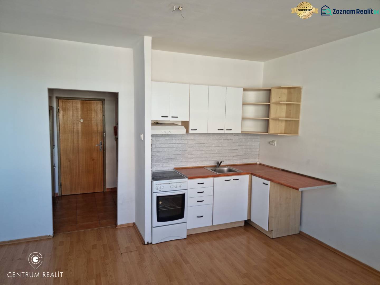 Studio apartment with entrance, kitchen, and floor with wood decor.