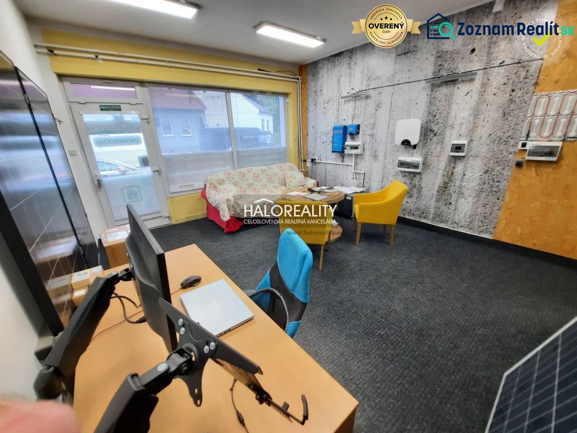 Office with carpet, computers, sofa, and colorful chairs.