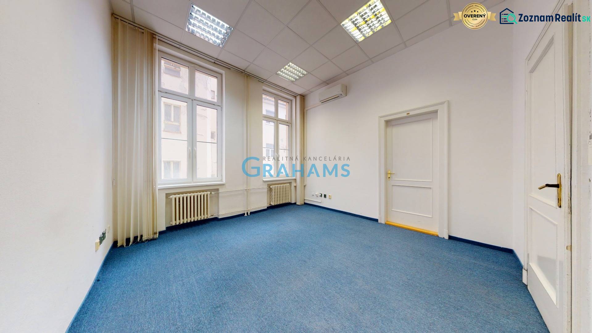 Offices with a tiled ceiling, blue carpet, and large windows.
