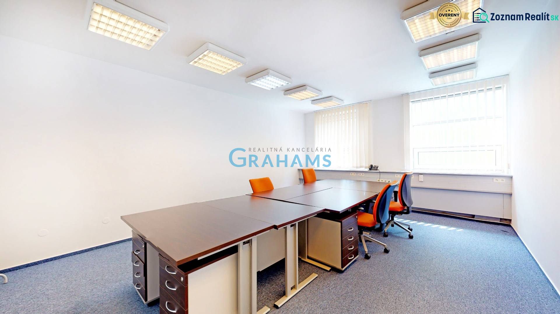 An office with orange chairs and a corner window, the room equipped with curtains.