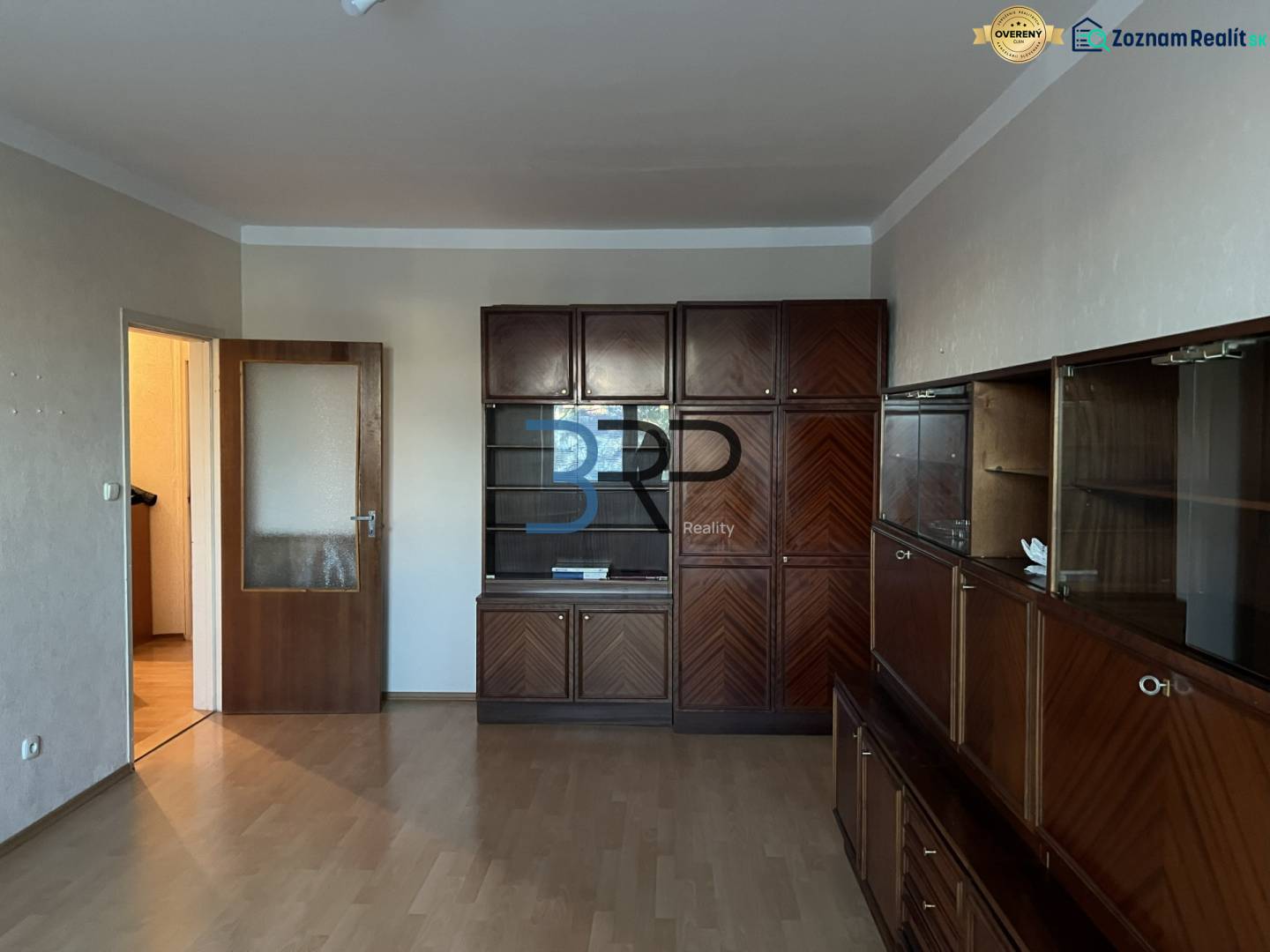 Living room in a two-room apartment with a large wooden living room set and a floor with a wooden decor.