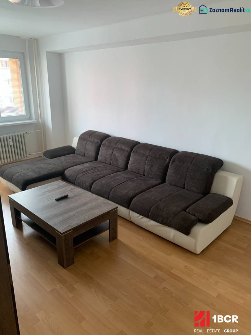 A sofa with a coffee table and a wooden decor floor in a 2-room apartment.