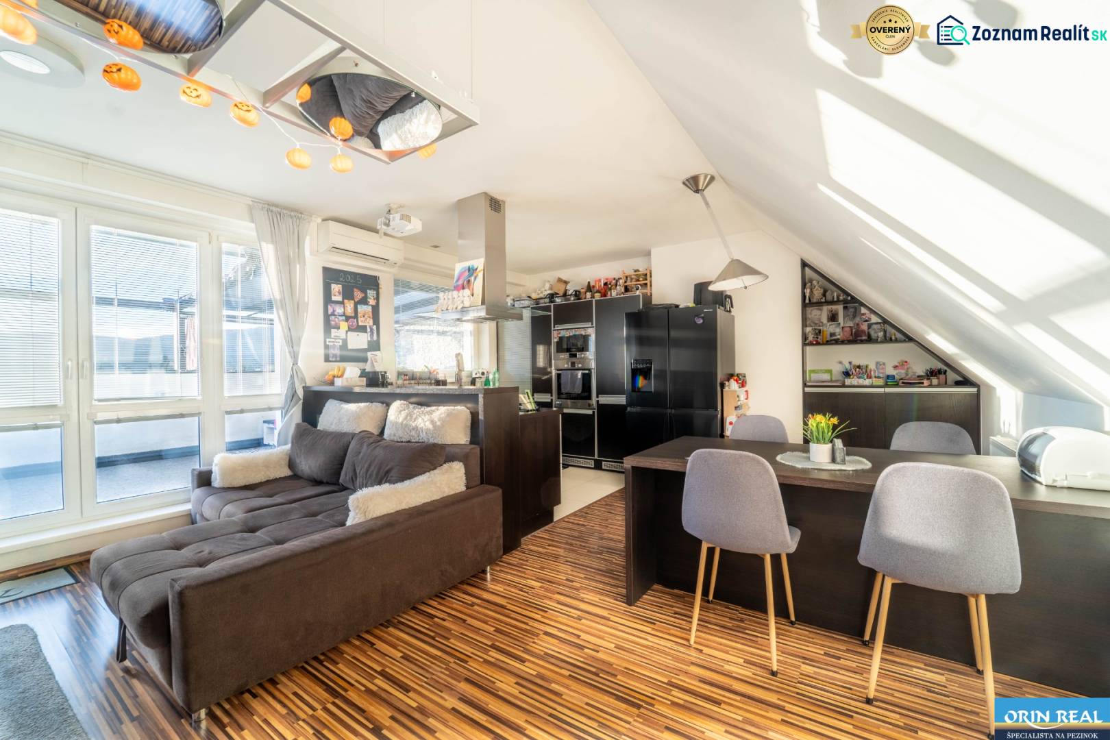 Living room with a kitchen in a 2-room apartment with a wooden decor floor and a comfortable sofa.