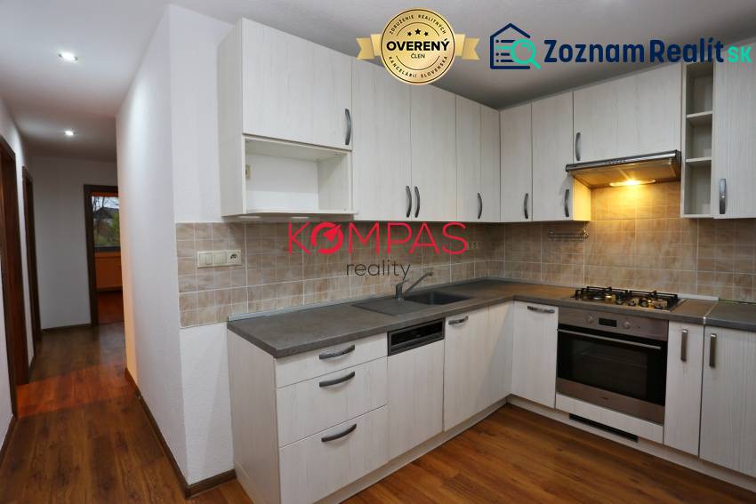 A kitchen with a kitchen unit and a wooden decor floor in a 3-room apartment.