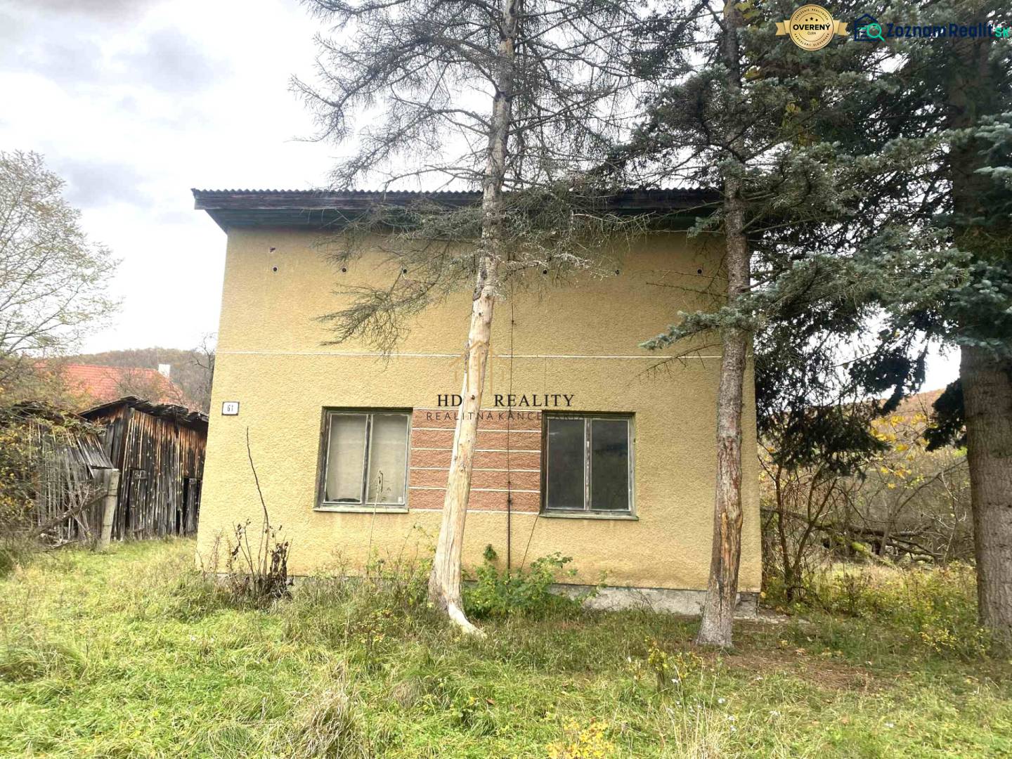 A family house in Rykynčice, surrounded by trees with a sloped plot and a wooden extension.
